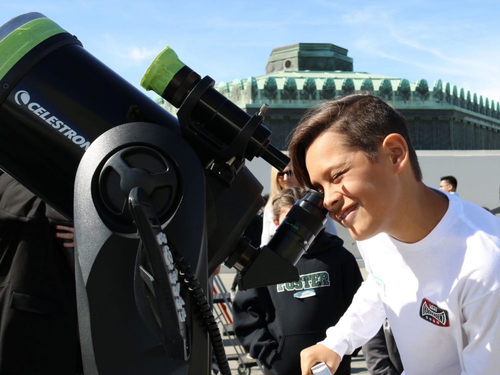 A boy looks through a telescope at Griffith Observatory.