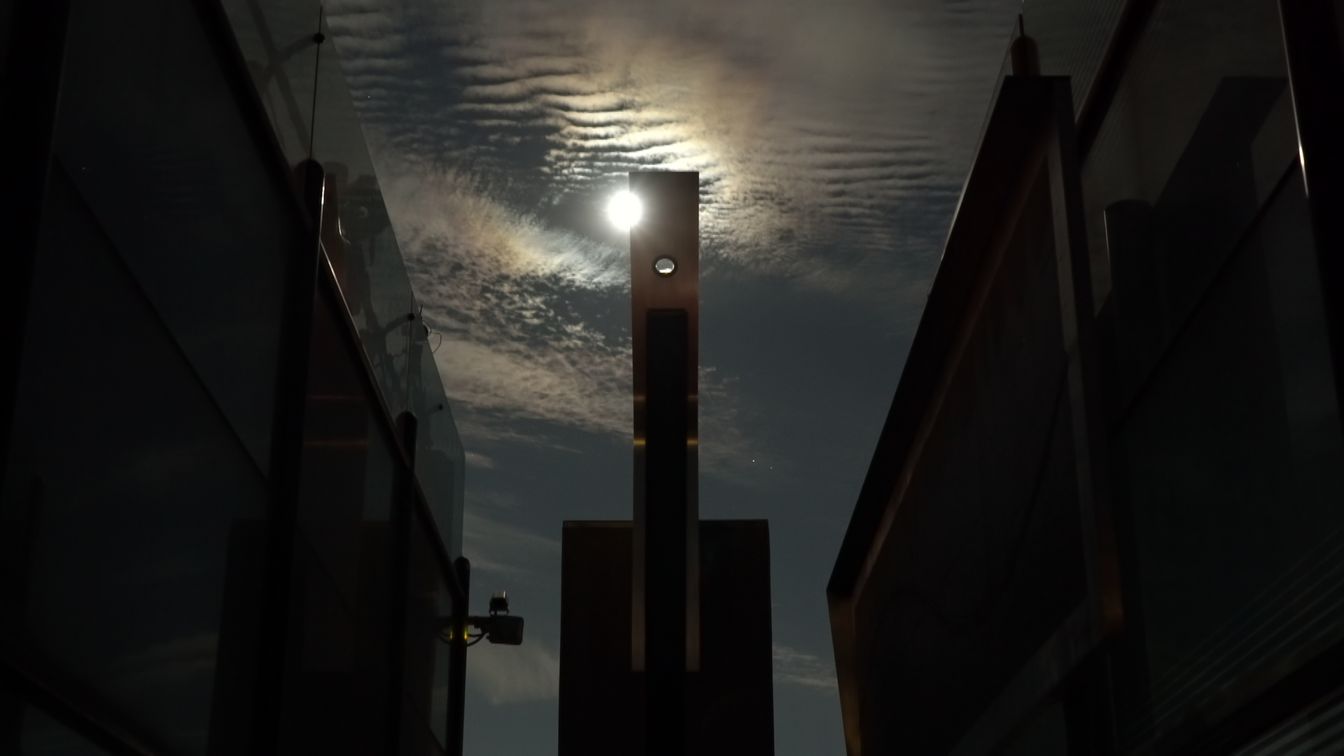 The moon crossing over the aluminum monolith.